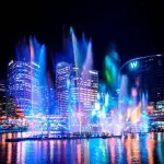 Stunning Sydney Harbour night cityscape featuring dazzling colourful lights, water fountains, and iconic skyscrapers on a Vivid Lights Cruise.