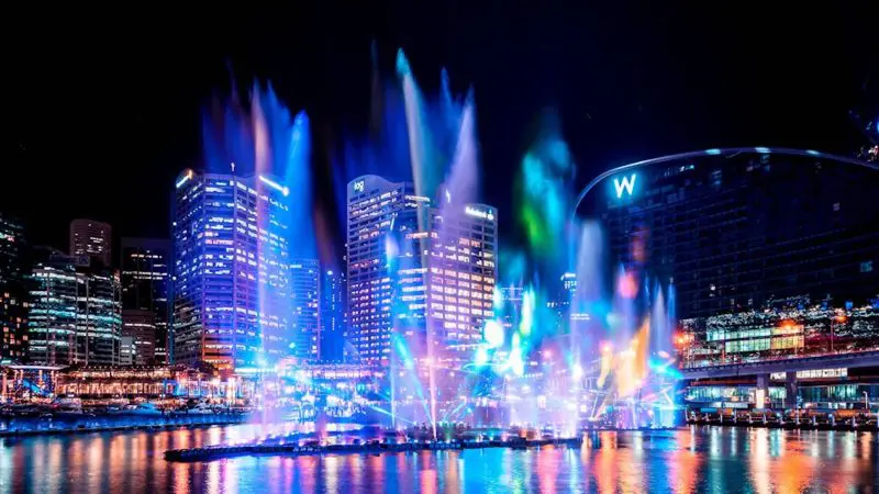 Stunning Sydney Harbour night cityscape featuring dazzling colourful lights, water fountains, and iconic skyscrapers on a Vivid Lights Cruise.