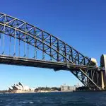 Sydney Harbour glows with the Bridge, Opera House, and skyline sparkling under clear blue skies—ideal for a top-rated Aussie Bites cruise.