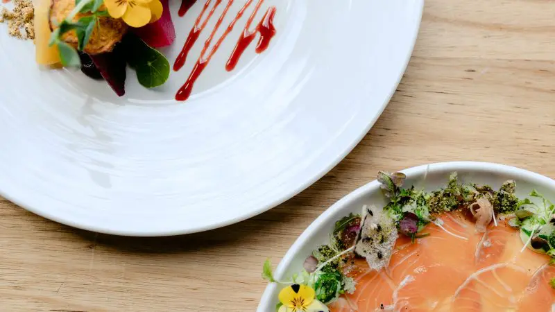 Gourmet salmon on greens and fresh veg served on white plates—ideal dining for a Coal River Valley Wine and Gin Safaris experience.