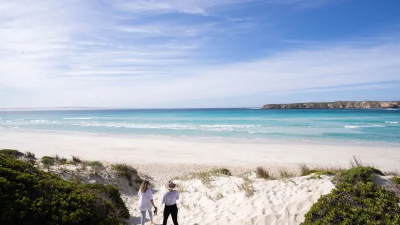 Adventurers stand atop pristine white sand dunes, taking in breathtaking vistas on the 6 Day Eyre Peninsula Flinders Ranges Tour.
