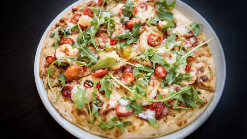 Gourmet pizza with fresh rocket, cherry tomatoes, and melty cheese served at Sorrentos Restaurant on a Sundowner Cruise & Dine.