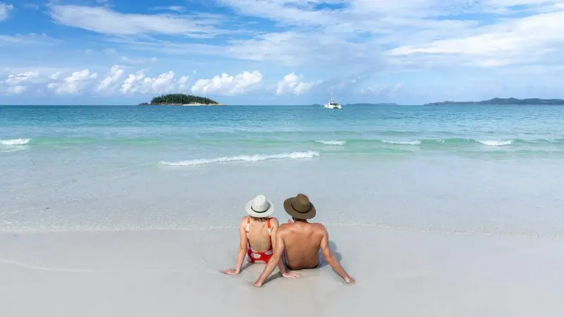 Couple sitting on beach at Whitehaven beach