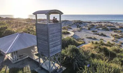 Discover Wanaka’s iconic tall wooden lookout tower, perched on the beach with panoramic views of sand dunes, sea, and sunset scenery.