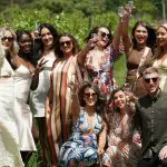Smiling friends toast together outdoors under sunny skies during a Yarra Valley winery tour, enjoying a relaxed group experience.