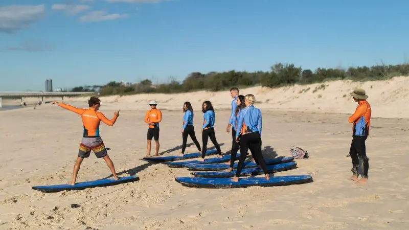 Expert surf instructor guides a 2-hour beginner surfing lesson for ages 13+ on the beach, teaching key techniques and water safety.