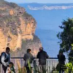 Group of four at panoramic Blue Mountains lookout on guided day tour with waterfall walk and social lunch, stunning scenic views.