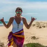 Smiling woman in sunglasses and swimming costume flashes shaka signs on a 1 Day Whale Watching Port Stephens tour, enjoying the adventure.