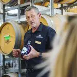 Expert guide leads a 1 Day Hunter Valley Wineries Tour from Sydney; wine barrels line Colourful Collective Travel winery's vibrant path.