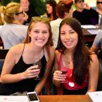 Two women savour red wine outdoors on a 1 Day Hunter Valley Wineries Tour from Sydney with Colourful Collective Travel, scenic vineyard views.