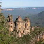 The Three Sisters—iconic sandstone pillars—tower over a lush forested valley in the Blue Mountains All-Inclusive Day Tour.