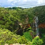 Majestic waterfall plunges over striking orange cliffs, a must-see highlight of the Blue Mountains All-Inclusive Signature Day Tour.