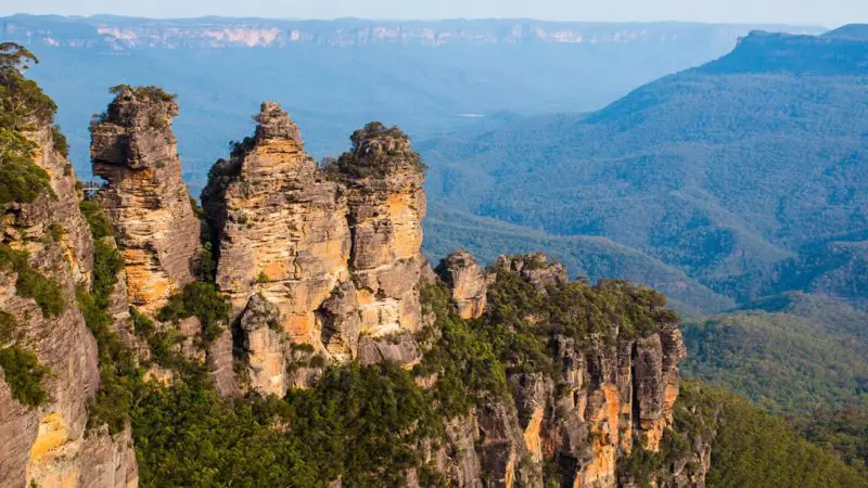 The iconic Three Sisters rock formations tower above lush forest, a must-see Blue Mountains highlight on the Explorer Bus Hop On Hop Off tour.