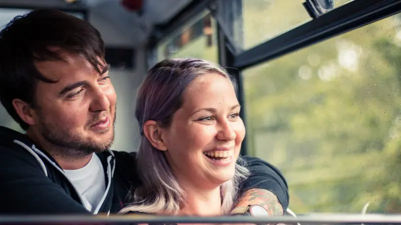 A joyful man embraces a happy woman by a bright window as they imagine their Boomerang Pass One Hour Sightseeing Tour experience.