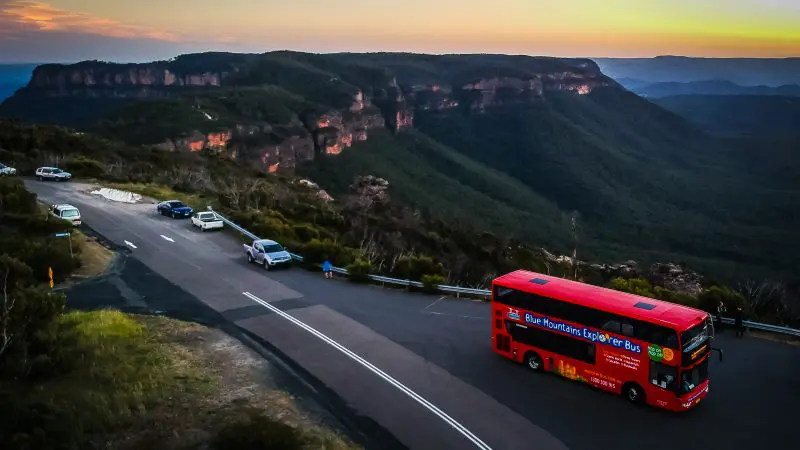Experience breath-taking sunset views as a red tour bus tours scenic Boomerang Pass on a one-hour mountain sightseeing adventure.