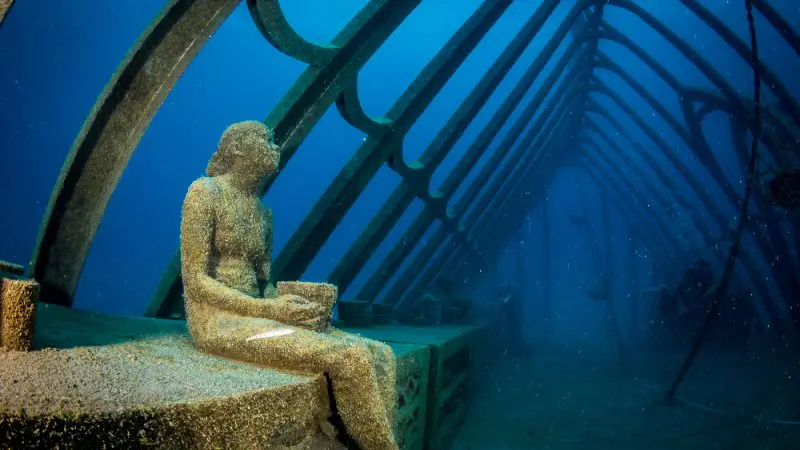 Discover a coral-encrusted statue inside a metal frame at Great Barrier Reef’s Moua, an exclusive underwater attraction for certified divers.