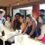 Guests savour a Yarra Valley wine tasting, watching an expert pour premium wines into glasses at a stylish bar during the event.