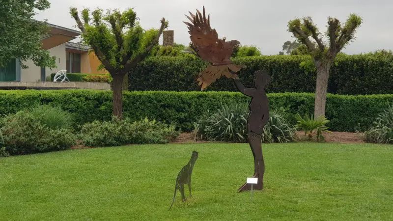 Striking metal sculptures of a person, bird, and dog grace lush green lawns—ideal photo spot during your Yarra Valley wine tasting tour.