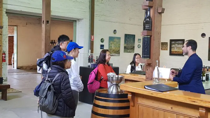 Wine enthusiasts experience Yarra Valley wine tasting at a rustic winery, engaging with expert staff for premium Australian wines.