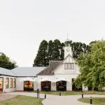 Elegant building with a clock tower, lush trees, and outdoor seating—ideal setting for gourmet wine tasting lunch and premium gin tasting.