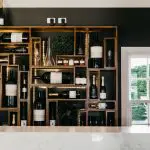 Sunlit wooden shelves showcase premium wine bottles and crystal glasses, creating an inviting gourmet wine tasting lunch atmosphere.