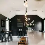 Chic winery tasting room with dramatic black walls, elegant floral counter, and stylish bar stools—ideal for gourmet wine tasting events.