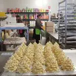 Rows of festive white chocolate Christmas trees showcased at Rayners Orchard Tour 1 in a vibrant, popular bakery kitchen setting.