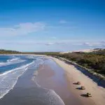 Aerial view of Fraser Island 4WD camping tour vehicles driving along scenic sandy beach, Island Expeditions K'gari Tours adventure.