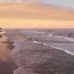 4WD vehicle cruising along Fraser Island’s sandy beach at sunset during an Island Expeditions Kgari Tours camping adventure.