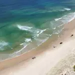 Aerial view of 4WD vehicles driving along pristine sandy beach—perfect for Fraser Island Tag Along Tours from Noosa or Rainbow Beach.