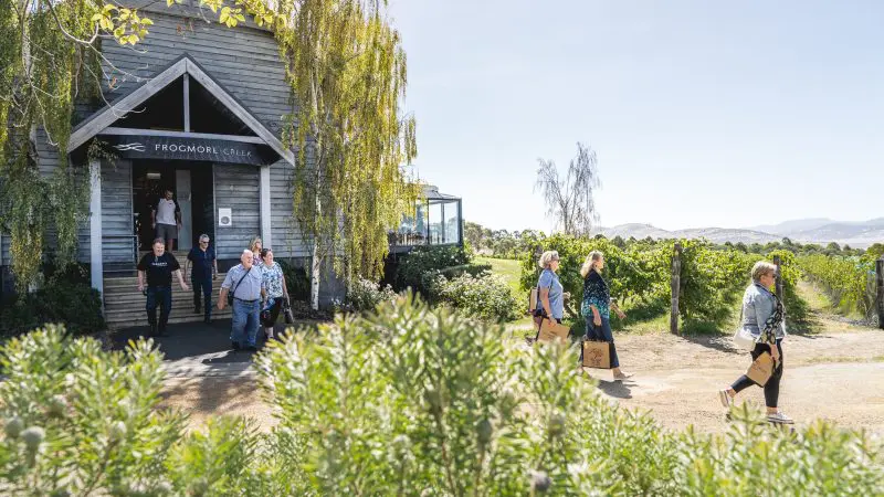 Guests leave a charming rustic building beside lush vineyards during a Coal River Valley Wine & Gin Safaris Private Day Tour experience.