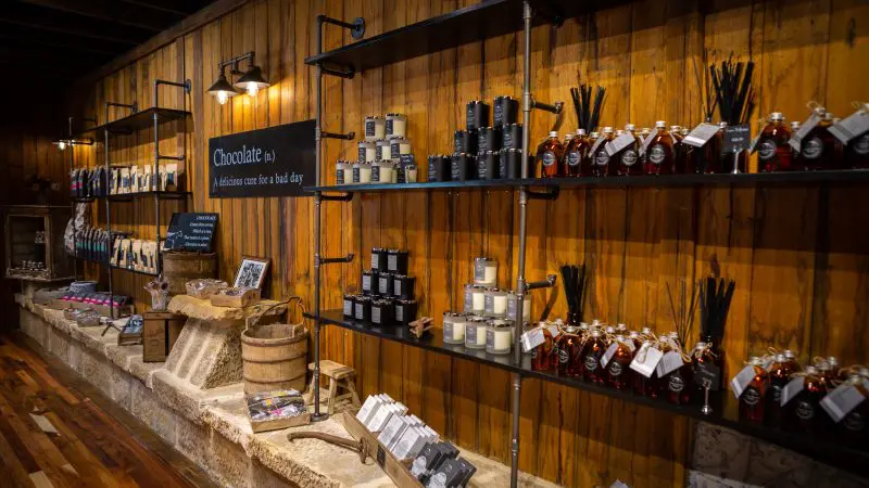 Rustic shop shelves near Tasman Safaris Port Arthur Harbour Cruise showcase artisan candles, reed diffusers, and local honey jars.