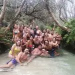 Happy group in swimwear poses in a scenic creek during a Kgari Safari Tour on Fraser Island, enjoying an unforgettable Australian adventure.