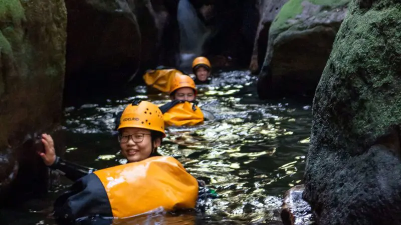 Adventurers in helmets and life jackets navigate Twister & Rocky Creek Canyons on an exhilarating Double Canyon Adventure tour.