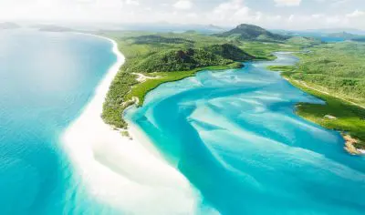 Stunning aerial view of a tropical coastline with clear blue skies, ideal for an East Coast Explorer or 27-day adventure tour.