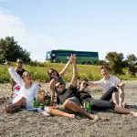 A group of friends relax and enjoy a classic New Zealand beach day, sitting together on golden sand under the sun by the sea.
