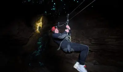 Adventurer in safety helmet traverses a rope, experiencing the exhilarating thrill of a signature New Zealand Kiwi Classic challenge.