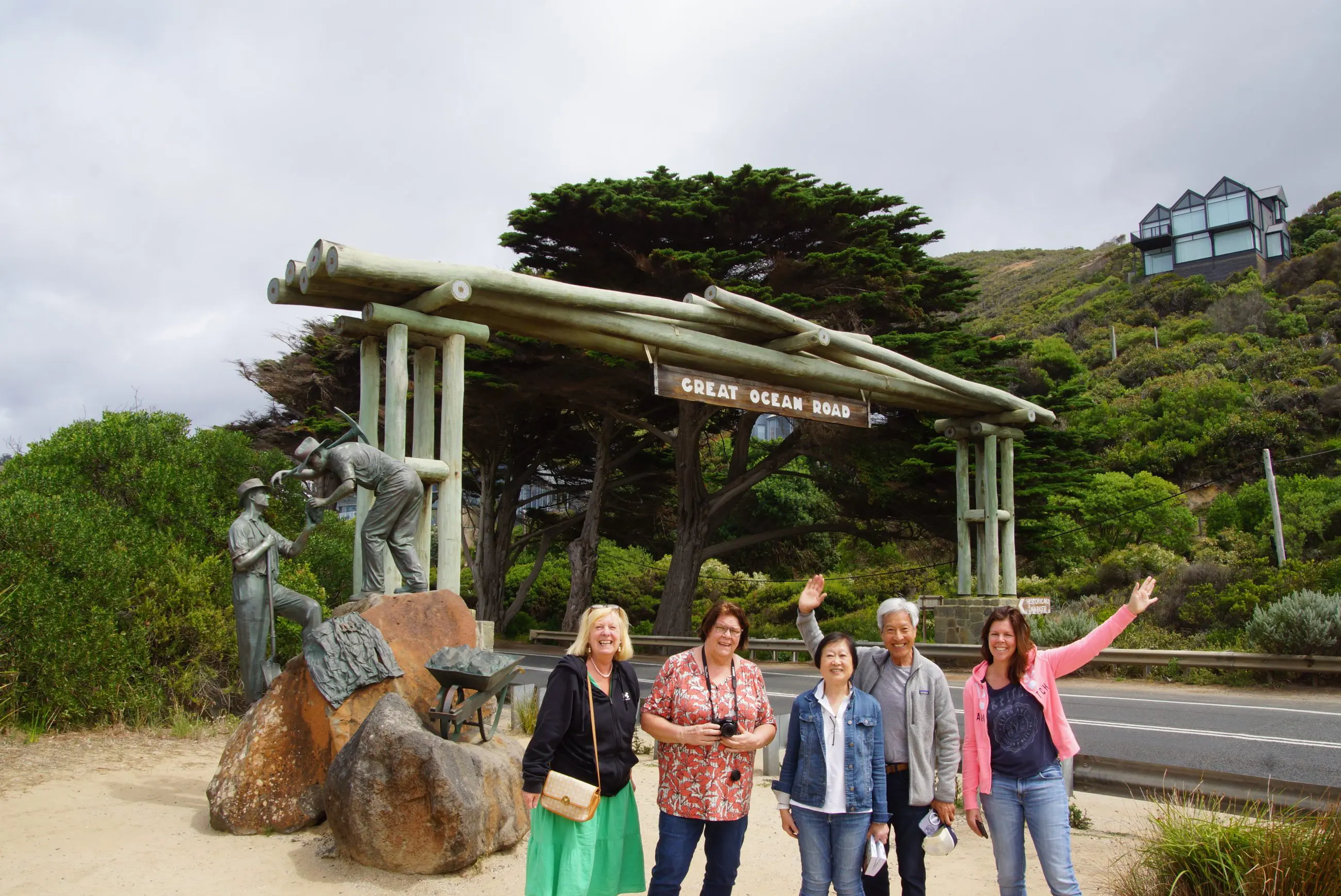Five women smiling and waving at the iconic Great Ocean Road Memorial Arch during a 4-day, 3-night Great Ocean Road and Beyond tour.