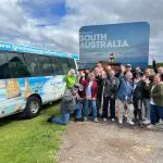 Travellers wave beside a tour van at the 