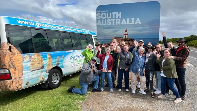 Travellers wave beside a tour van at the 
