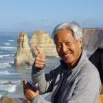 Happy man giving a thumbs up in front of iconic Great Ocean Road rock formations on 4-day, 3-night guided tour adventure.