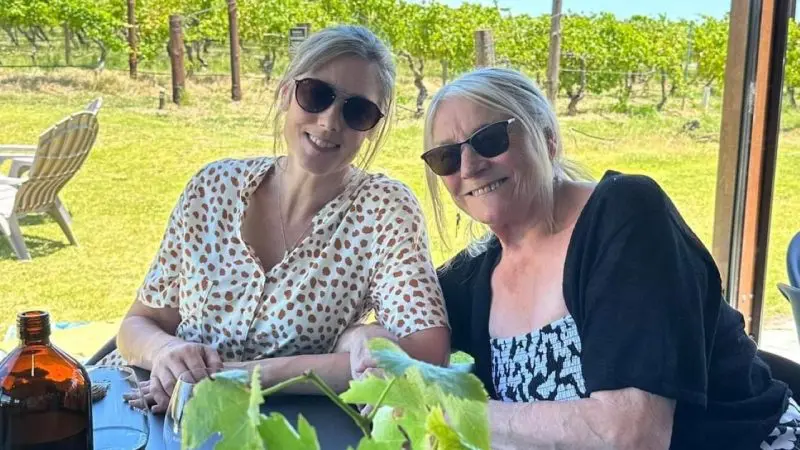 Two women wearing stylish sunglasses enjoy a wine tasting at an outdoor table on an Adelaide Highlights full day tour experience.