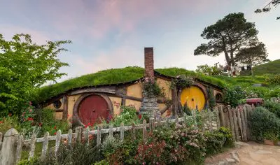 Authentic hobbit house with iconic round door and lush grassy roof, reminiscent of Hobbiton Film Set near Rotorua Geothermal Valley.