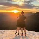 Romantic couple embraces on a rocky Blue Mountains cliff at sunset during a 1 Day Wilderness Tour, overlooking scenic valleys.