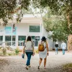 Two women approach a modern building, experiencing the ultimate Phillip Island Penguin Parade and Koalas Tour with exclusive viewing.