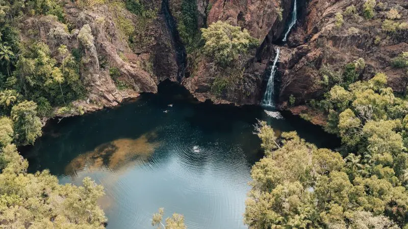Stunning aerial view of Kakadu Litchfield National Park rocky waterfall, lush forest surrounds, 4WD safari tour highlights serene nature.