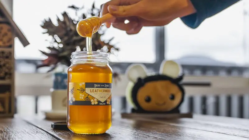 A close-up of honey flowing from a dipper into a Leatherwood honey jar on a Huon Valley Safaris Private Day Tour in Tasmania.