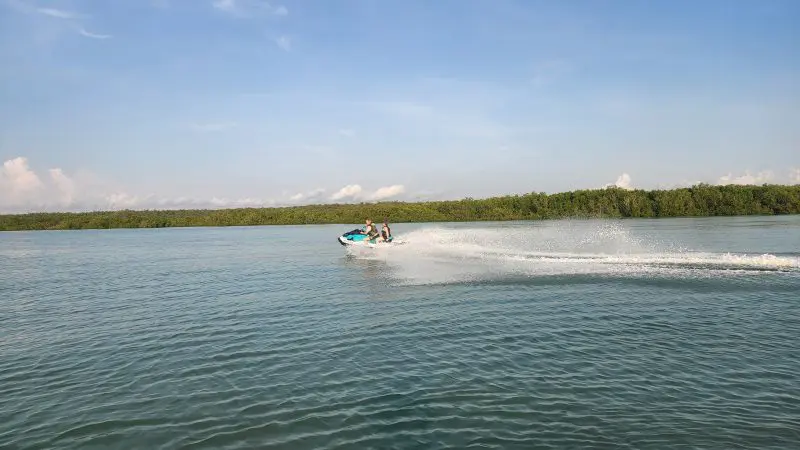 Two people riding a jet ski across a serene, blue lake under a crystal-clear sky, evoking thrilling adventure and outdoor excitement.