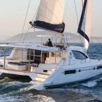 Experience the luxury Whitehaven Dreamer catamaran gliding on Whitsunday waters, expertly helmed for ultimate sailing adventure.