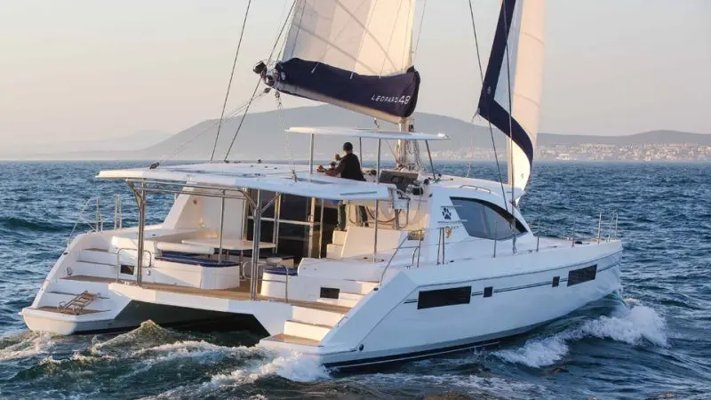 Experience the luxury Whitehaven Dreamer catamaran gliding on Whitsunday waters, expertly helmed for ultimate sailing adventure.